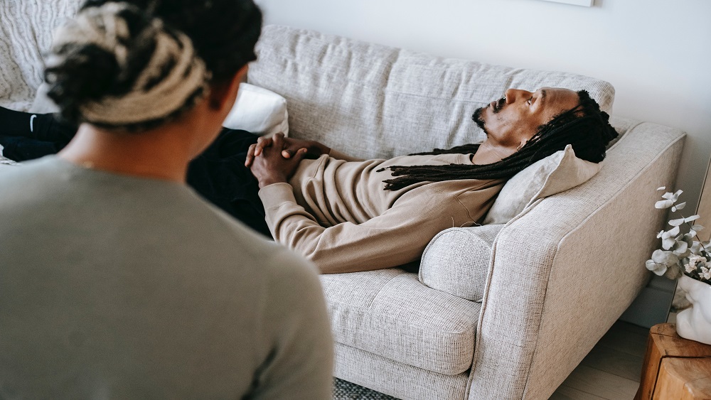 men laying on couching and therapist on chair